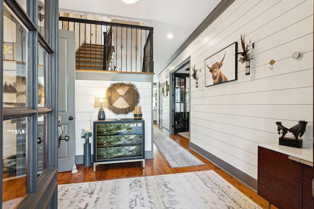 corridor featuring hardwood / wood-style flooring, wooden walls, and crown molding