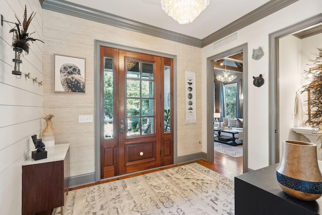 foyer entrance featuring ornamental molding, a chandelier, and hardwood / wood-style floors