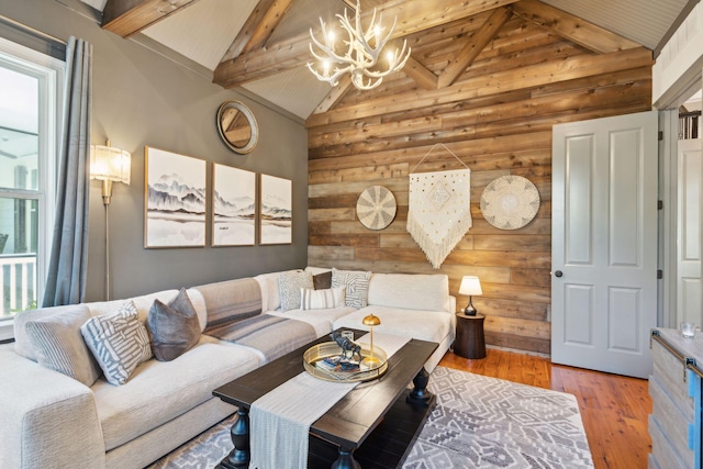 living room featuring wood-type flooring, rustic walls, a notable chandelier, high vaulted ceiling, and beam ceiling