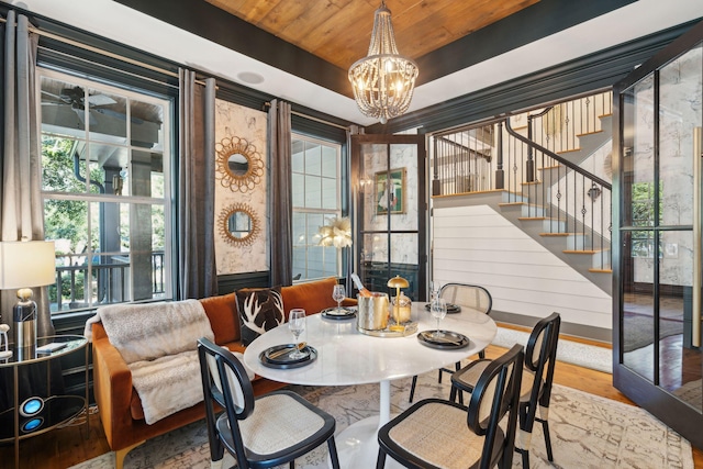 dining space with an inviting chandelier, a raised ceiling, wood ceiling, and hardwood / wood-style floors