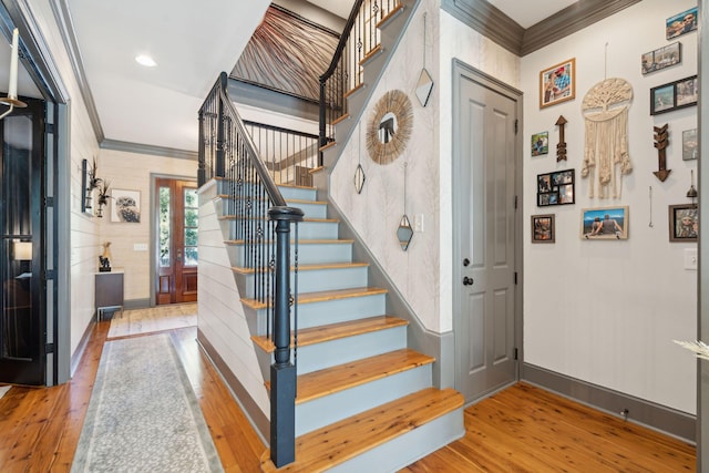 stairway with ornamental molding and hardwood / wood-style floors