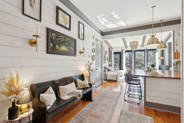 living room with beam ceiling, hardwood / wood-style floors, ornamental molding, and wood walls