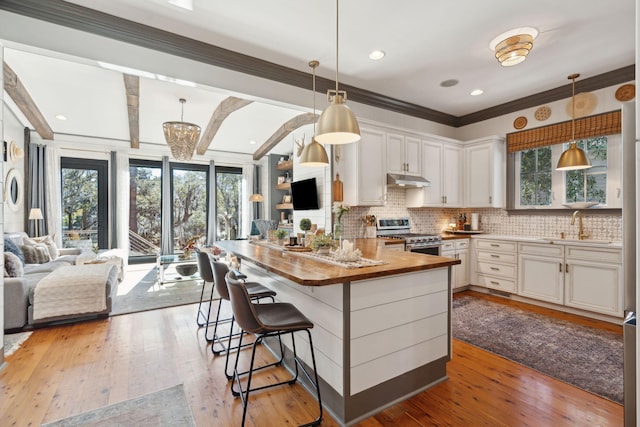 kitchen with white cabinets, wooden counters, stainless steel range oven, and light hardwood / wood-style flooring