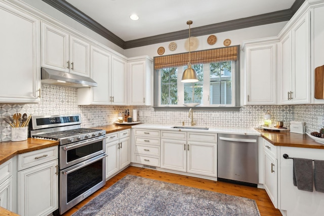 kitchen with decorative light fixtures, stainless steel appliances, wooden counters, white cabinets, and sink