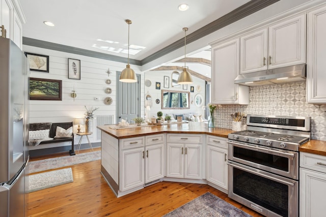 kitchen featuring stainless steel appliances, decorative light fixtures, white cabinetry, light hardwood / wood-style floors, and wooden counters