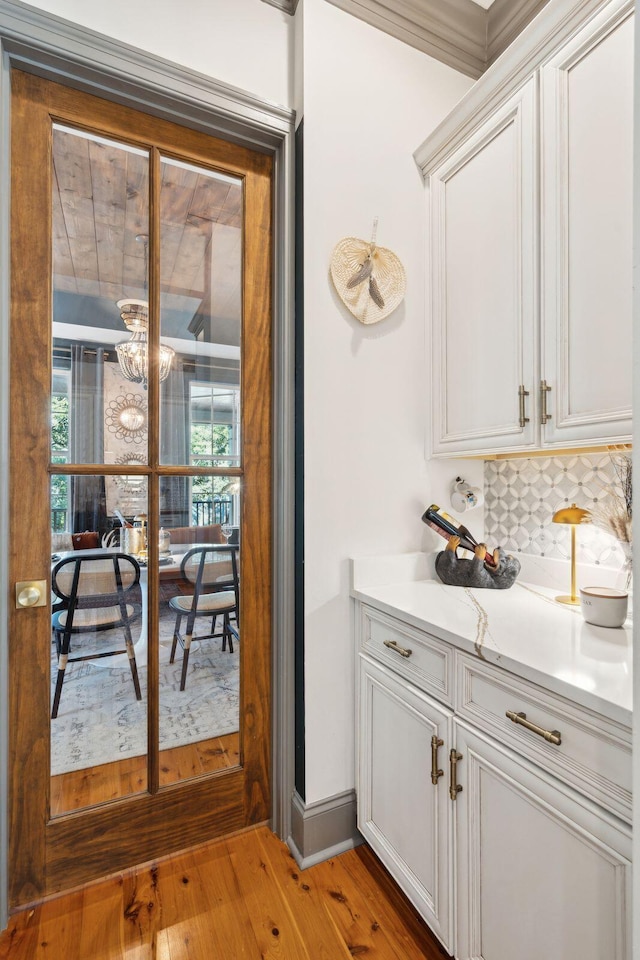 bar with decorative backsplash, white cabinetry, hardwood / wood-style floors, and a healthy amount of sunlight