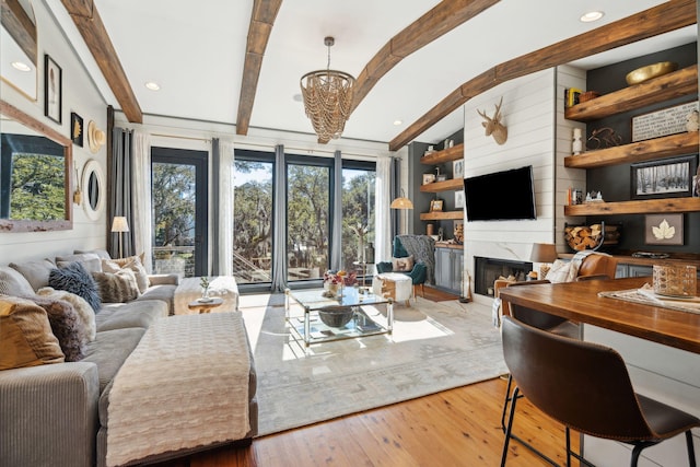 living room with wooden walls, wood-type flooring, lofted ceiling with beams, a high end fireplace, and a chandelier