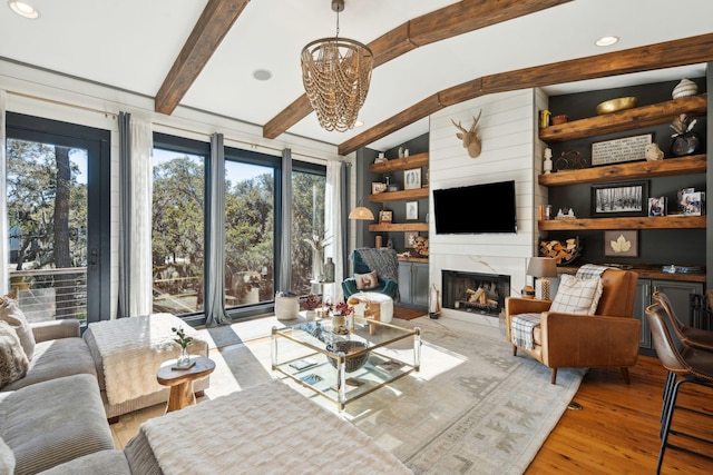 living room with a premium fireplace, light wood-type flooring, vaulted ceiling with beams, and an inviting chandelier