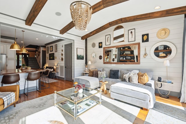 living room featuring an inviting chandelier, beam ceiling, wooden walls, and hardwood / wood-style floors