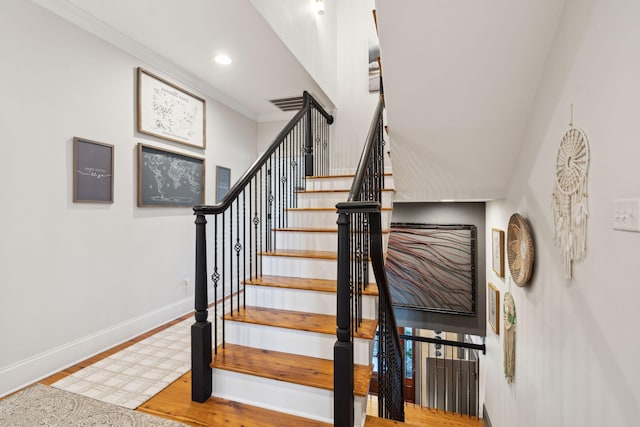 stairway with ornamental molding and hardwood / wood-style flooring