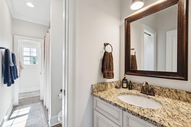 bathroom featuring toilet, ornamental molding, and vanity