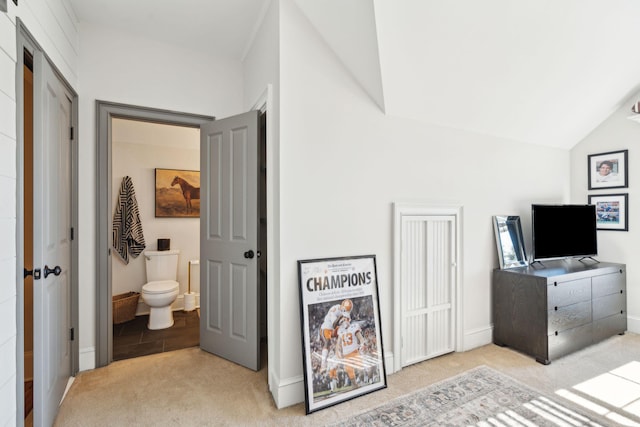 carpeted bedroom featuring lofted ceiling and ensuite bath