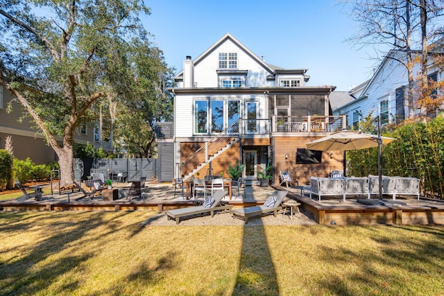 back of property featuring a deck, a lawn, and a sunroom