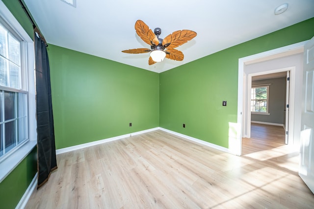 spare room featuring light wood-style flooring, baseboards, and a ceiling fan