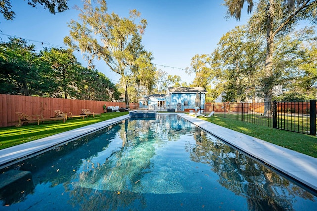 view of swimming pool featuring an outbuilding, a pool with connected hot tub, a lawn, a fenced backyard, and a storage structure