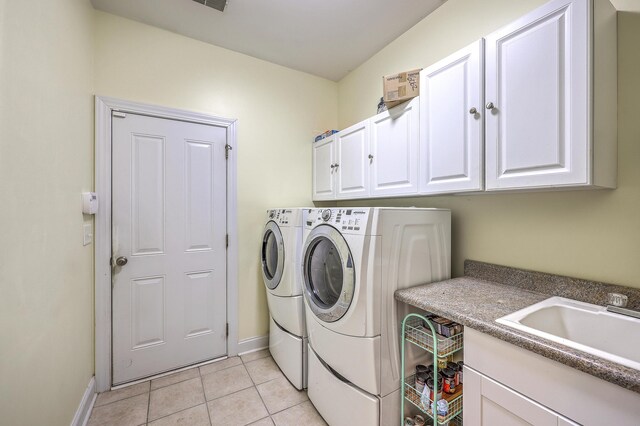 laundry room featuring washing machine and clothes dryer, cabinet space, a sink, baseboards, and light tile patterned floors