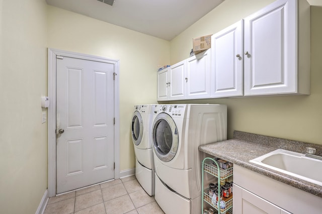 laundry room featuring washer and dryer, light tile patterned flooring, cabinet space, a sink, and baseboards