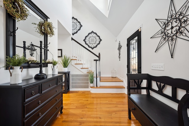 entrance foyer featuring lofted ceiling with skylight and light hardwood / wood-style floors