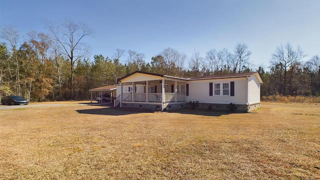 manufactured / mobile home featuring a front lawn, a carport, and covered porch