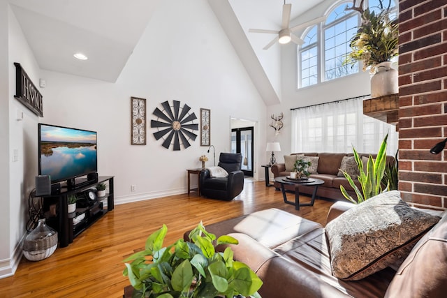 living room with a high ceiling, wood-type flooring, and ceiling fan