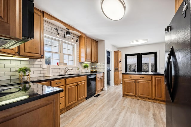 kitchen with tasteful backsplash, light hardwood / wood-style floors, sink, and black appliances