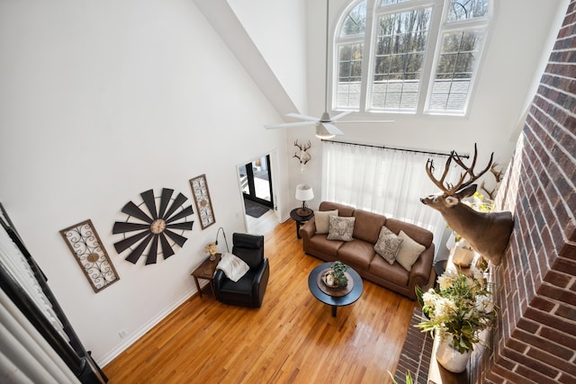 living room with a high ceiling, hardwood / wood-style floors, and ceiling fan