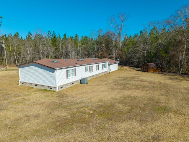 back of house with a storage unit, central air condition unit, and a lawn