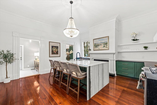 kitchen with hanging light fixtures, a kitchen island with sink, dark wood-type flooring, and a kitchen bar