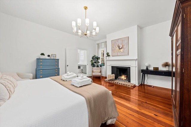 bedroom featuring hardwood / wood-style flooring, a fireplace, and a chandelier