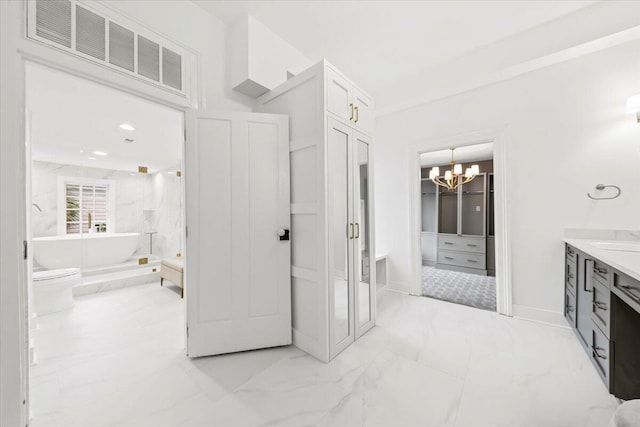 bathroom featuring vanity, a washtub, and an inviting chandelier