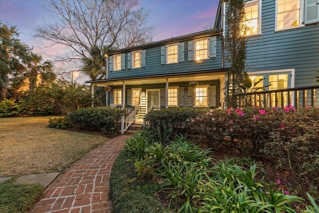 view of front of property featuring covered porch and a lawn