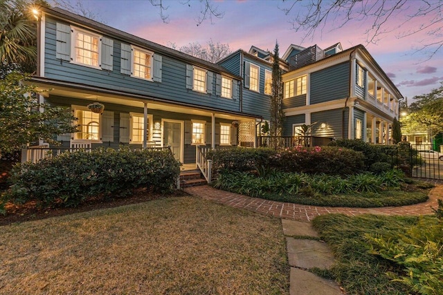 view of front of home with covered porch and a lawn