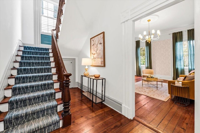 stairway with hardwood / wood-style flooring, a healthy amount of sunlight, and a notable chandelier