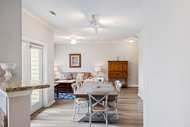 dining space with ceiling fan, ornamental molding, rail lighting, and light hardwood / wood-style flooring