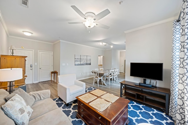 living room featuring wood-type flooring, ornamental molding, and ceiling fan