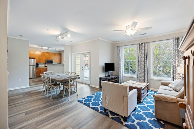 living room featuring ceiling fan, ornamental molding, rail lighting, and light hardwood / wood-style flooring