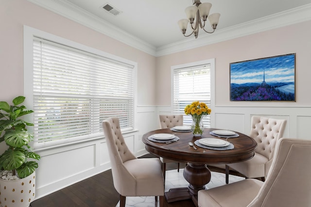 dining area with hardwood / wood-style flooring, ornamental molding, and a notable chandelier