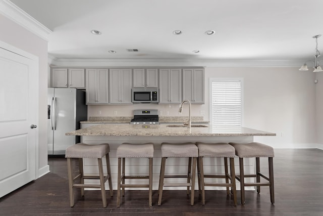 kitchen featuring stainless steel appliances, a kitchen island with sink, gray cabinetry, and light stone counters