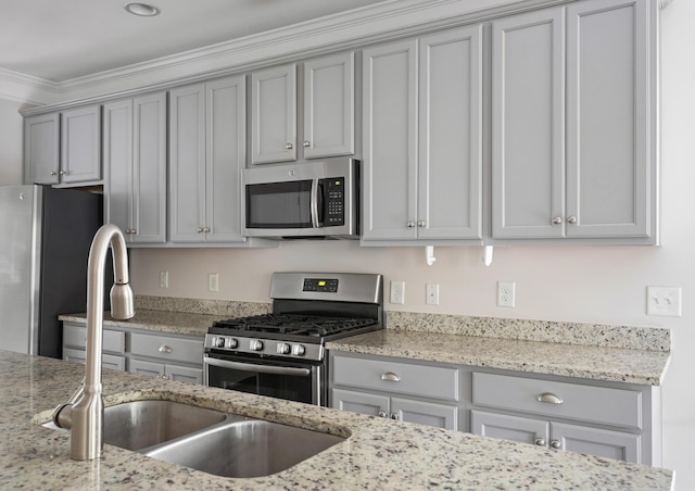 kitchen featuring light stone counters, sink, gray cabinets, and appliances with stainless steel finishes