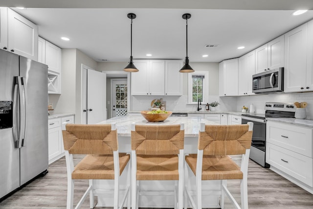 kitchen with stainless steel appliances, a kitchen island, and white cabinets