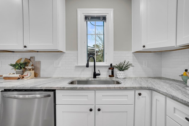 kitchen with white cabinetry, sink, light stone counters, and stainless steel dishwasher