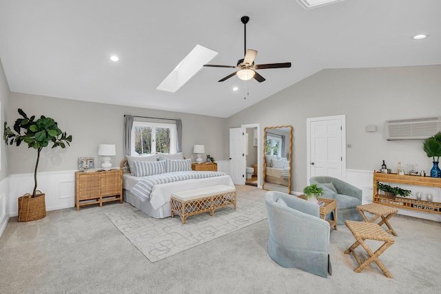 carpeted bedroom with vaulted ceiling with skylight, a wall mounted AC, and ceiling fan