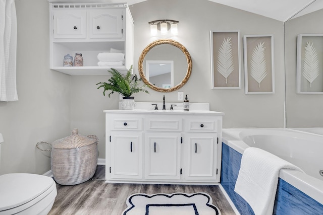 bathroom with lofted ceiling, toilet, wood-type flooring, vanity, and a relaxing tiled tub