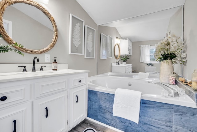 bathroom featuring vanity, tiled bath, and vaulted ceiling