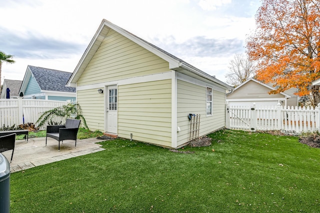 back of house featuring an outbuilding, a yard, and a patio