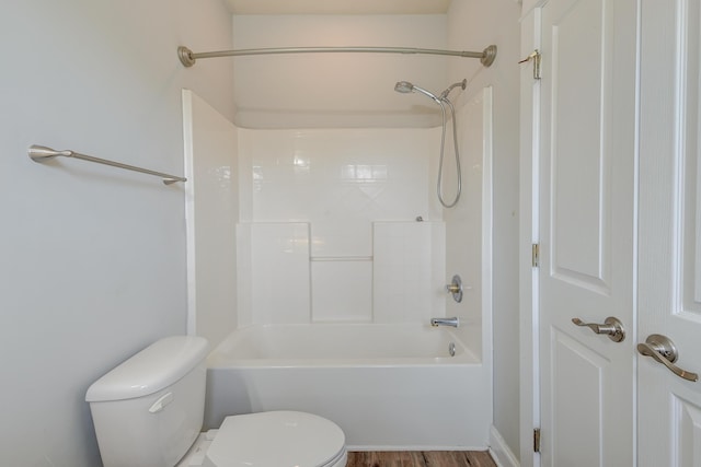 bathroom with hardwood / wood-style floors, tub / shower combination, and toilet