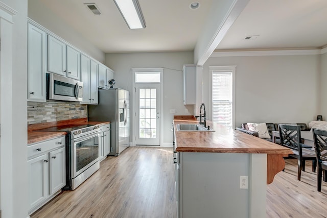 kitchen with appliances with stainless steel finishes, light wood-type flooring, butcher block countertops, and sink