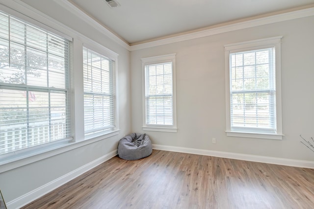 empty room featuring light wood-type flooring and crown molding