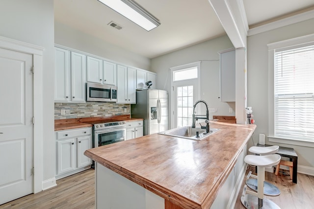 kitchen featuring a healthy amount of sunlight, sink, white cabinets, and stainless steel appliances