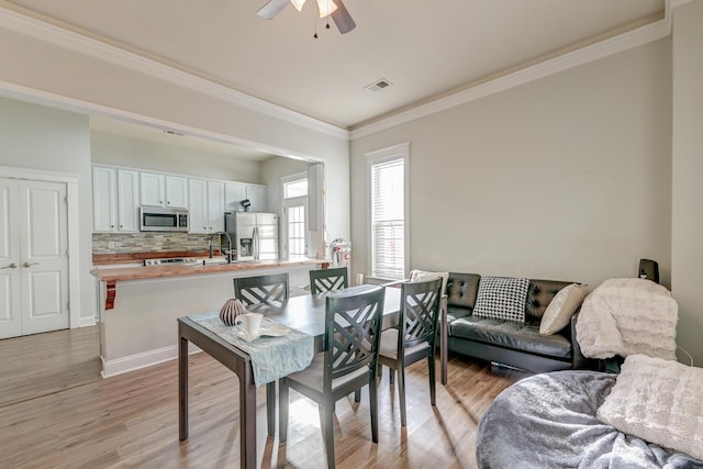 dining area with ceiling fan, ornamental molding, and light wood-type flooring